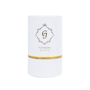 White cylinder serum packaging with gold foiling accents – A sleek white cylindrical box with elegant gold foiling, designed for luxury serum packaging, featuring the "Ceremony Gifts" logo prominently on the front.