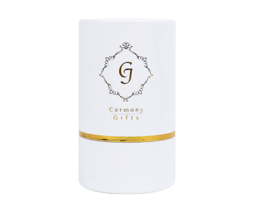 White cylinder serum packaging with gold foiling accents – A sleek white cylindrical box with elegant gold foiling, designed for luxury serum packaging, featuring the "Ceremony Gifts" logo prominently on the front.