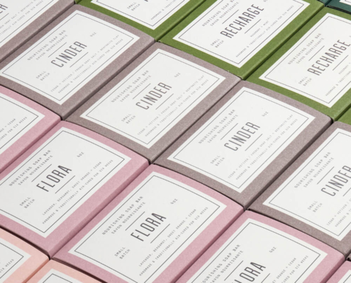 Rows of colorful soap packaging boxes in pink, green, and brown, featuring nature-inspired branding for retail and wholesale display.