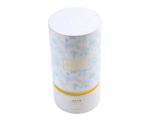 Foundation packaging tube standing upright, highlighting floral details and gold band.