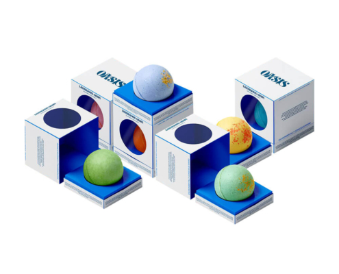 Collection of eco-conscious bath bomb packaging boxes, each holding colorful bath bombs, shown with blue accents and circular windows for product visibility.