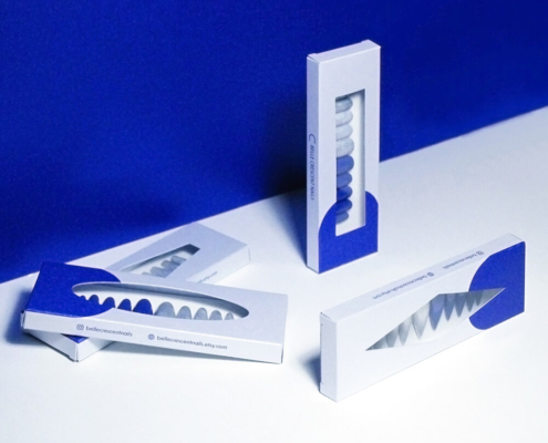 Press on nail packaging boxes arranged on a blue and white surface with nail sets inside.