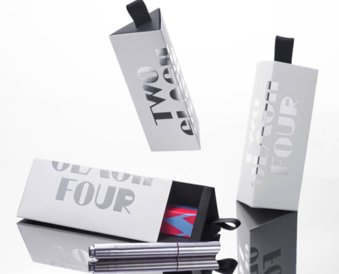 Multiple triangle lip gloss boxes with ribbon handles, showcasing a modern design and easy-to-open functionality.