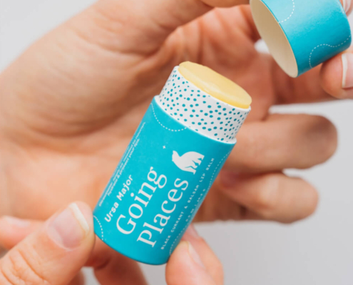 Hand opening a recyclable lip balm tube with ergonomic design, showing easy-to-use push-up feature and eco-friendly construction.