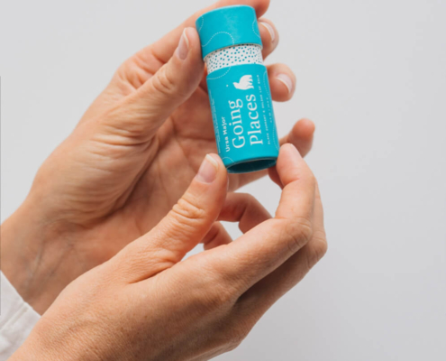 Hand holding a closed eco-friendly lip balm tube, highlighting compact size, ergonomic design, and sustainable cardboard material.