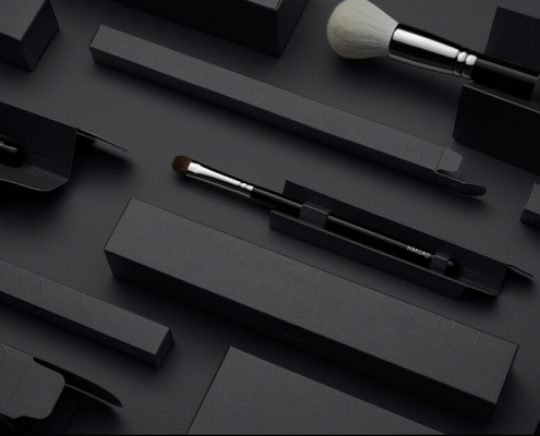 Close-up view of multiple black makeup brush boxes displayed neatly on a dark surface.