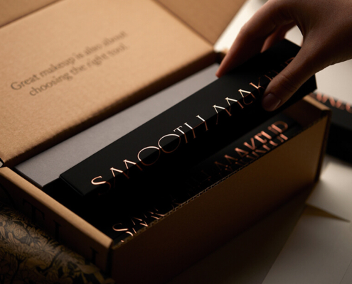 A hand placing a makeup brush box into eco-friendly cardboard packaging.