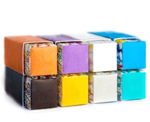 Close-Up of Stacked Custom Lipstick Boxes - Close-up of stacked lipstick boxes in shades like orange, purple, and blue, each with a unique artistic base.