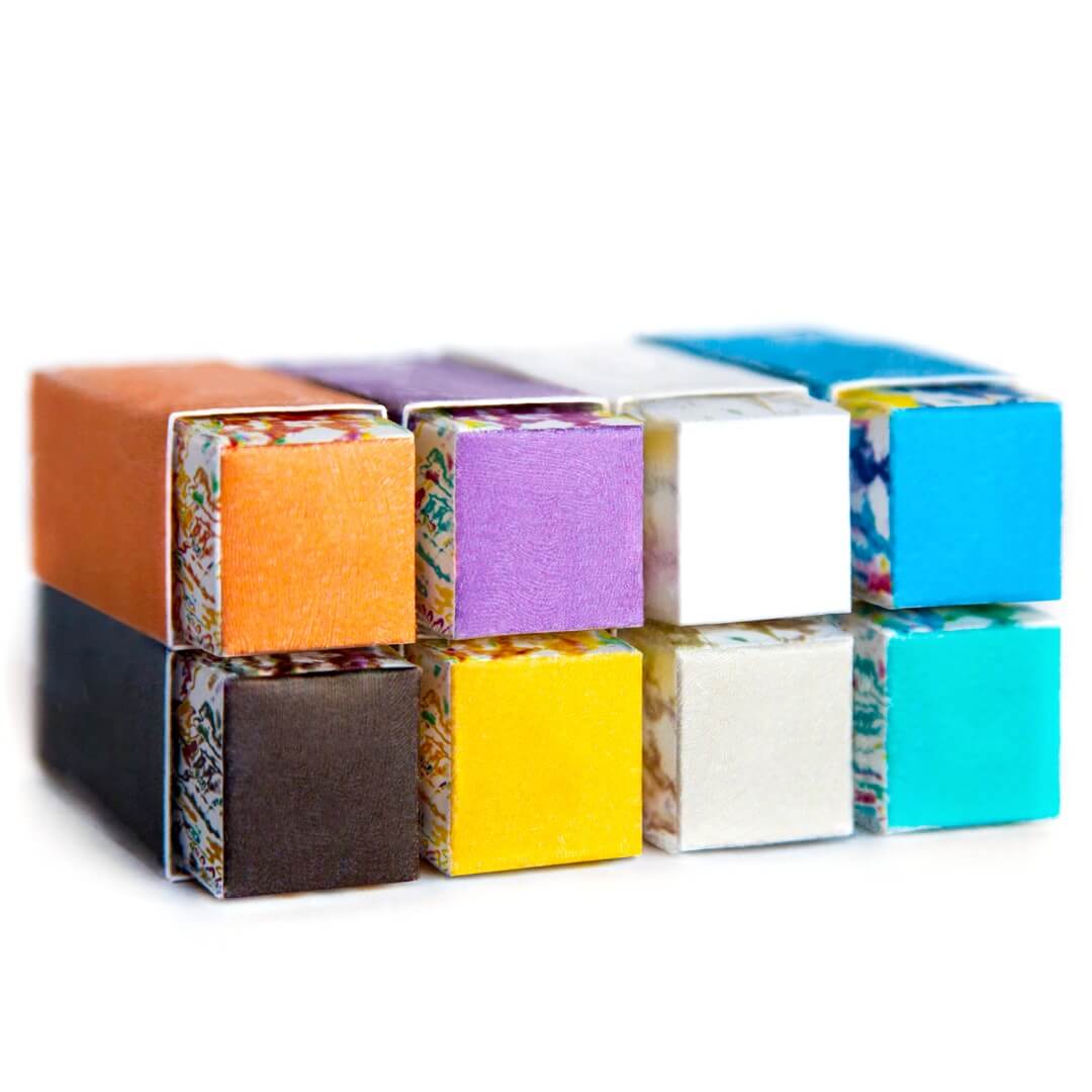 Close-Up of Stacked Custom Lipstick Boxes - Close-up of stacked lipstick boxes in shades like orange, purple, and blue, each with a unique artistic base.