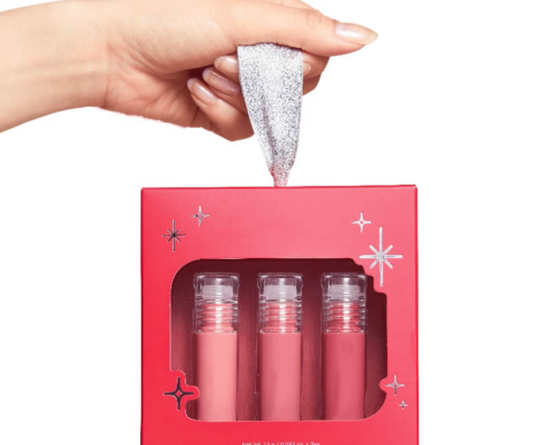 Hand holding the red lip gloss box set with a silver handle and three glosses inside