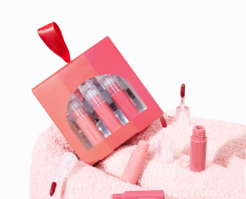 Red and pink gradient lip gloss box with three glosses and applicators on a soft fabric