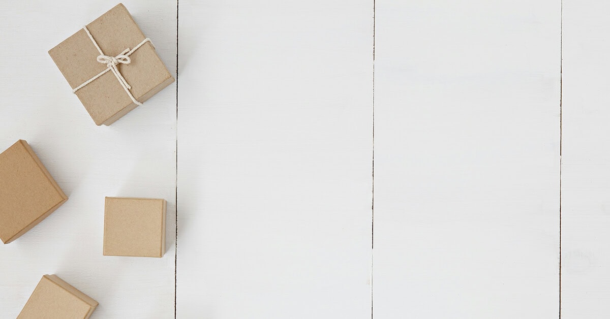 Multiple small kraft paper gift boxes tied with twine on a white wooden surface.