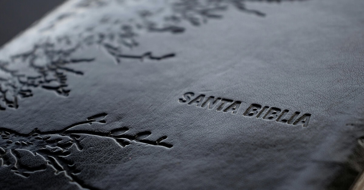 Close-up of a debossed leather Bible cover with detailed floral patterns and the text "SANTA BIBLIA."